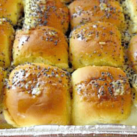 Golden brown dinner rolls topped with poppy seeds, perfectly baked and ready to serve.