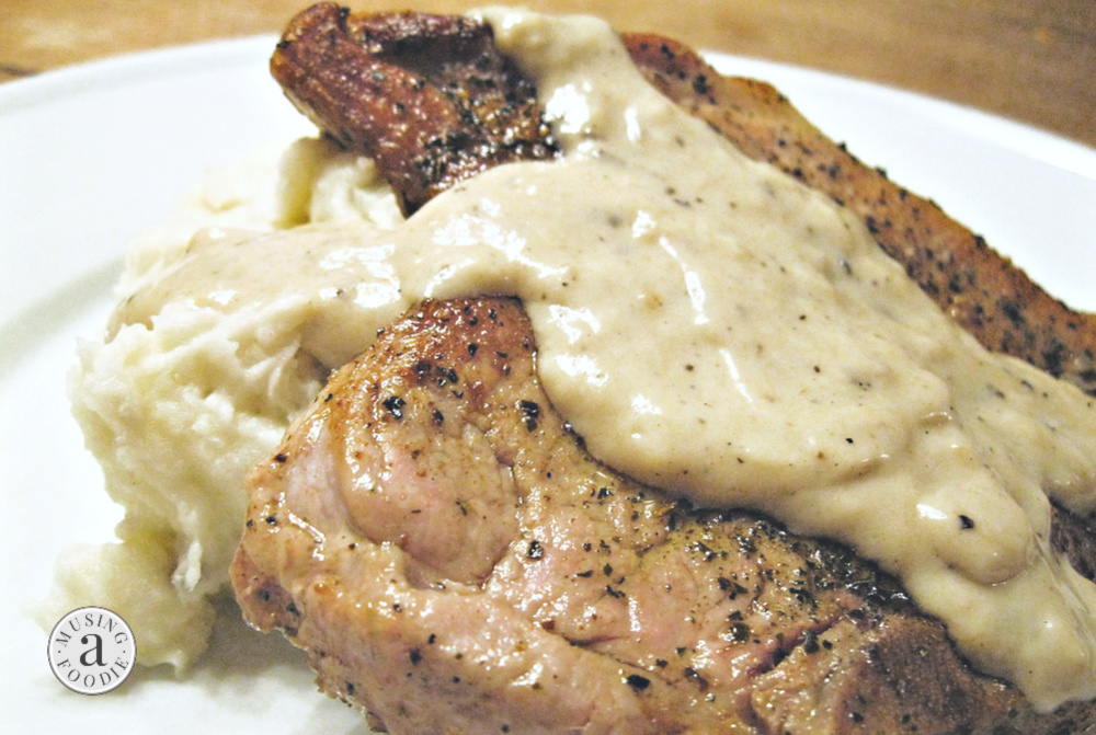 Seared juicy pork chops plated with mashed potatoes and pan gravy made in a cast iron skillet.