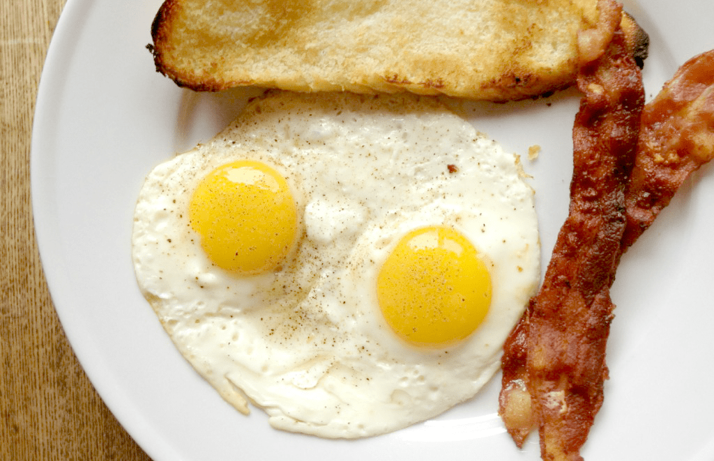 Delicious sunny-side-up eggs, crispy bacon, and golden toast on a classic breakfast plate.