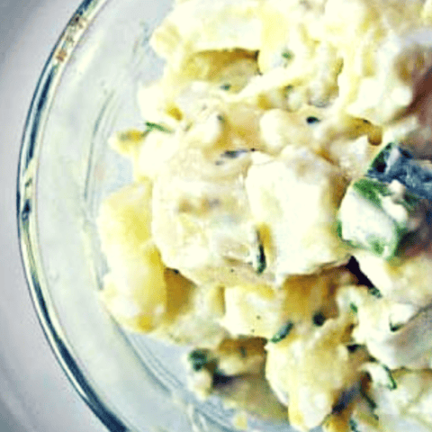 Delicious homemade potato salad with herbs in a glass bowl, perfect for gatherings.