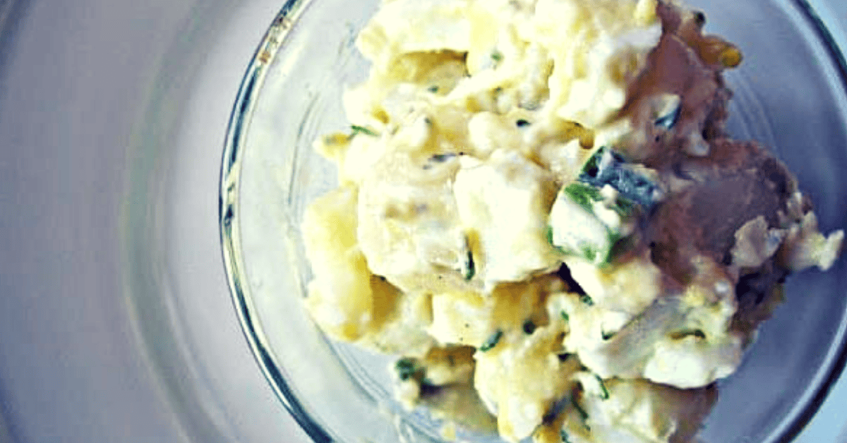Delicious homemade potato salad with herbs in a glass bowl, perfect for gatherings.