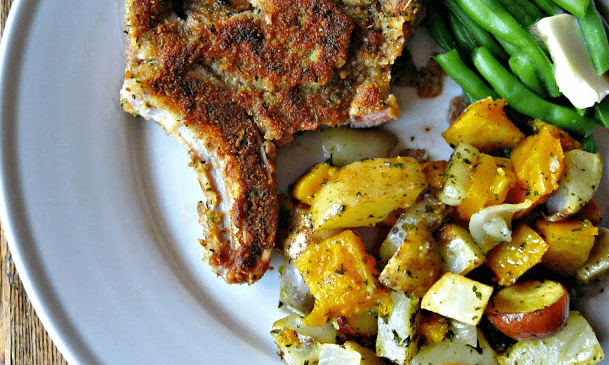 Delicious pork chop served with roasted vegetables and vibrant green beans for a balanced meal.
