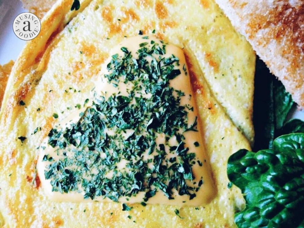 Close up of omelette made with cheese, spinach and lump crab meat and served with buttered toast.