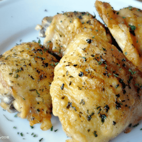 Crispy oven-fried chicken thighs garnished with fresh herbs for a delicious meal.