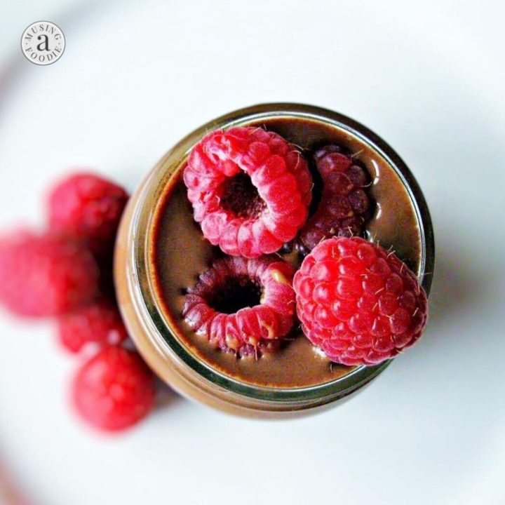 Chocolate mocha pudding topped with raspberries and served in a mason jar.