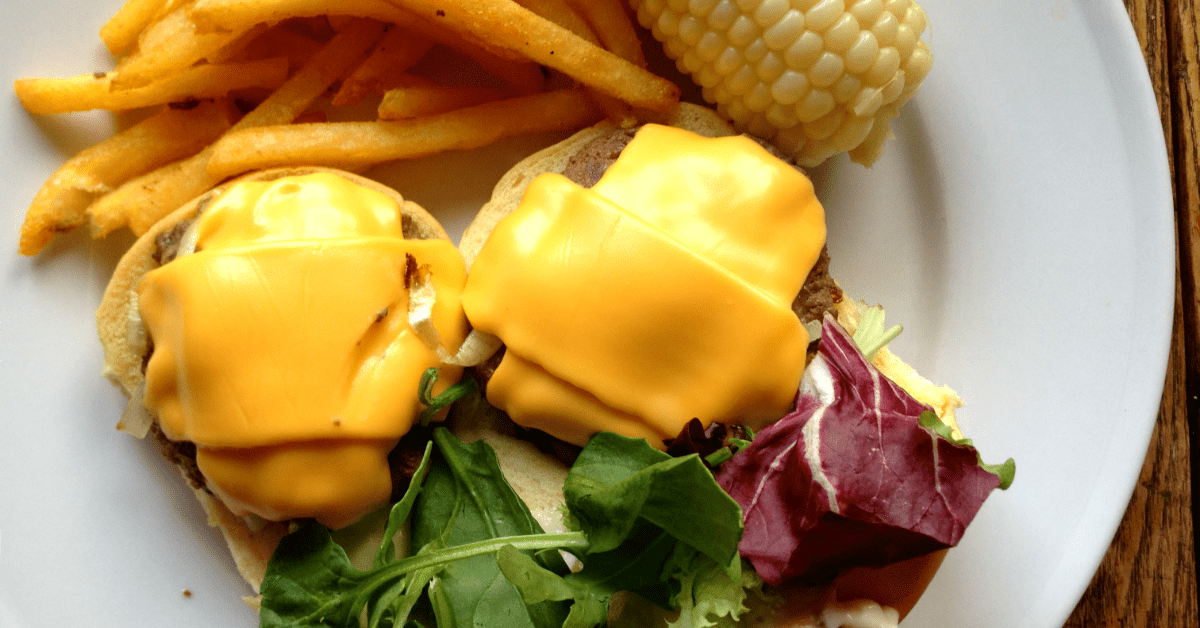 Delicious cheeseburgers with melted cheese, crispy fries, and fresh corn for a satisfying meal.