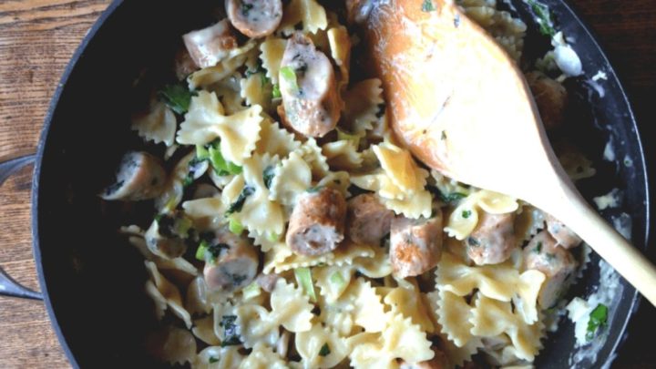 Skillet with faralle pasta cooked in a garlic cream sauce and served with seared chicken sausage.