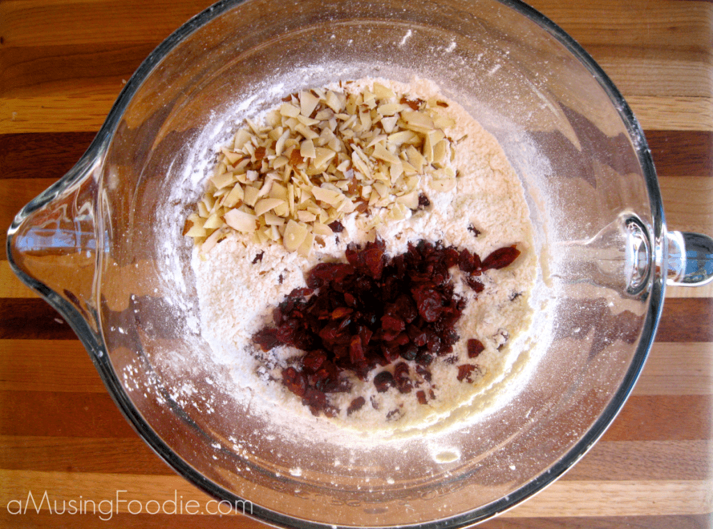 Dry ingredients with dried cranberries and slivered almonds in a mixing bowl.