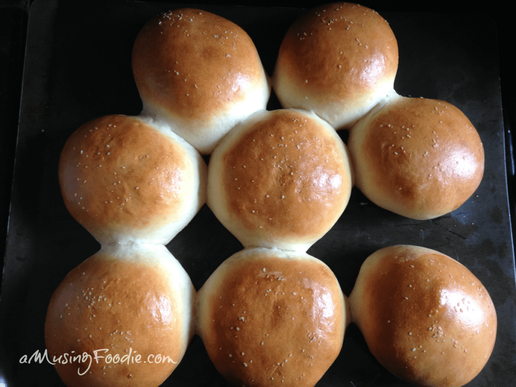 Eight hamburger buns with salted tops, freshly baked.