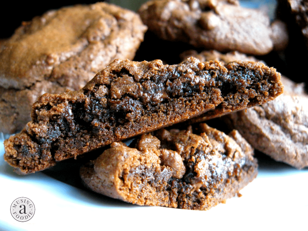 Close up side photo of a chocolate cookie cut in half. The inside looks darker and gooey.