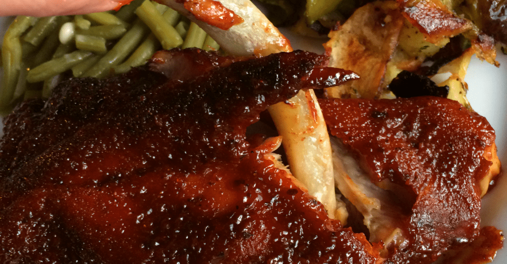 Tender BBQ ribs with glossy sauce served alongside vibrant green beans for a delightful meal.