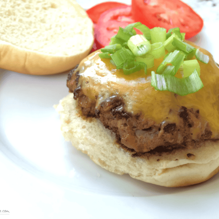 Mouthwatering cheddar burger topped with fresh green onions and juicy tomato slices.