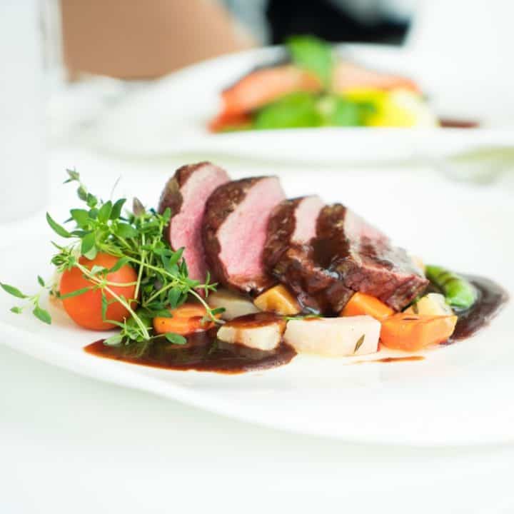 Elegant beef platter with vibrant vegetables and rich sauce, showcasing culinary artistry.