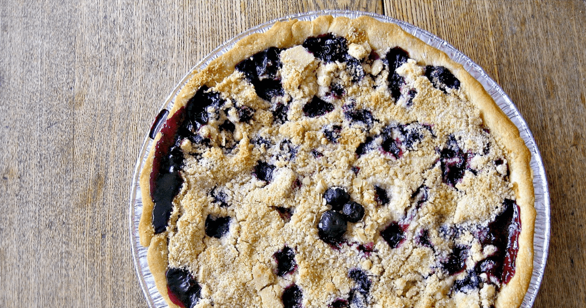 Delicious berry pie topped with crispy streusel on a rustic wooden surface.