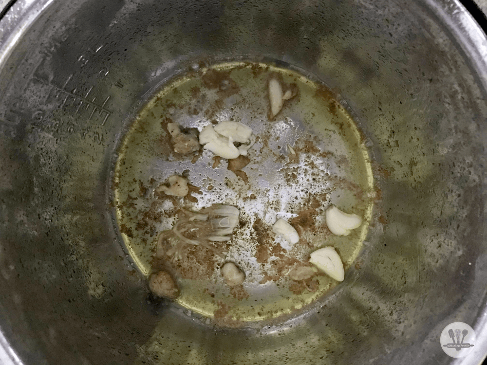 Sautéing garlic in the bottom of an Instant Pot with olive oil and frond from seared chicken.