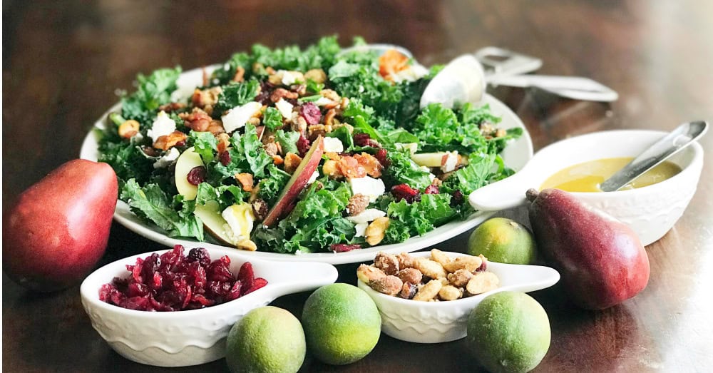 Fresh kale salad topped with fruits, nuts, and a light honey mustard dressing.