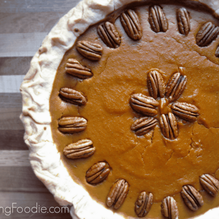 Homemade pumpkin pie topped with pecans, perfect for cozy fall gatherings and celebrations.