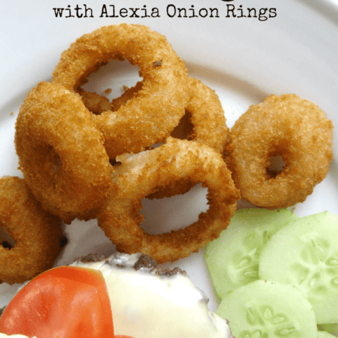 Delicious homemade cheeseburgers with crispy onion rings and fresh vegetables on a plate.