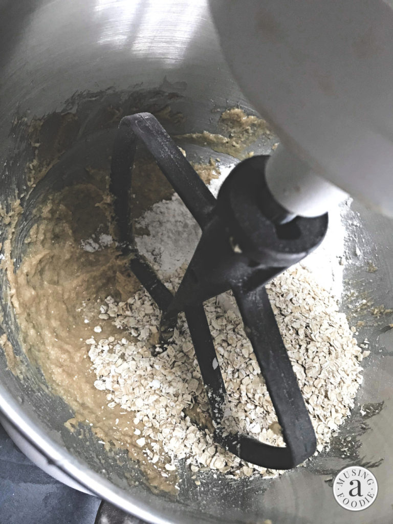 Oats and flour being added to cookie batter before being mixed.
