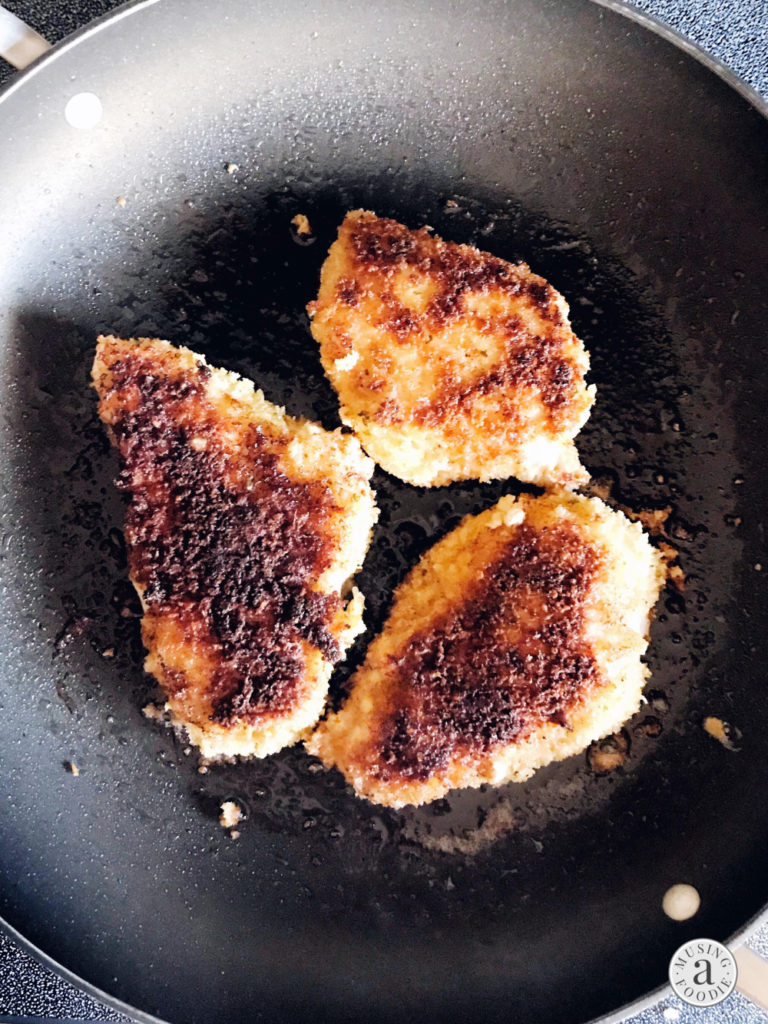 Panko crusted chicken seared on both sides in a skillet.