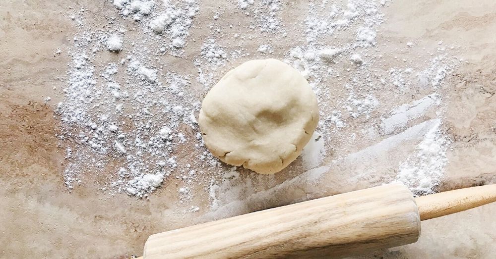 Disk of pie dough on a floured counter with a rolling pin.
