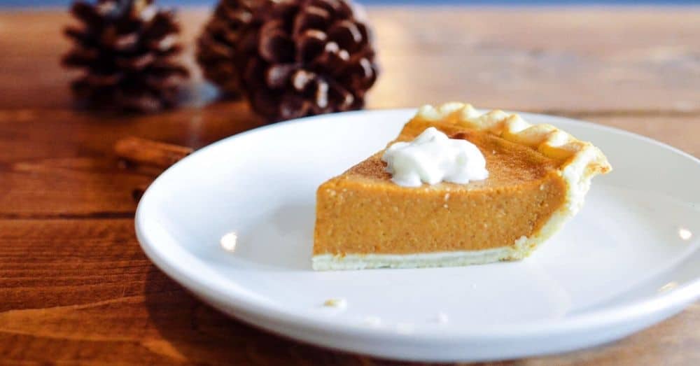 Irresistible pumpkin pie slice topped with whipped cream on a rustic wooden table.
